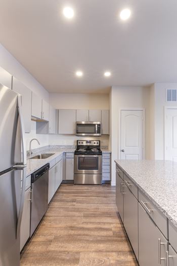 A modern kitchen with stainless steel appliances and wooden flooring.